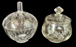 Duas bombonieres em cristal lapidado com tampas decorativas, detalhes em relevo, gravações florais e acabamento transparente. Medindo: 15 x 17 cm e 16 x 14 cm.