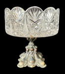 Centro de mesa em cristal lapidado com borda ondulada e rica lapidação geométrica. Base em metal trabalhado com detalhes em relevo apresentando folga na fixação peça. Medindo: 20 x 20 cm.