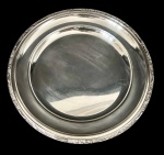 Meridional - Travessa redonda em metal prateado com borda decorada em relevo, acabamento polido com marcas de uso e riscos superficiais. Medindo: 33,5 cm.