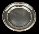 Meridional - Travessa redonda em metal prateado com borda decorada em relevo, acabamento polido com marcas de uso e riscos superficiais. Medindo: 30 cm.
