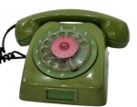 Antigo telefone de mesa em baquelite verde, modelo de disco rotativo, com fone original e cabo espiral, apresentando sinais de uso. Medindo: 20 x 12 x 14 cm.