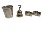 Conjunto com três peças em metal prateado, composto por um copo, uma pequena sineta com pegador decorativo e dois porta-guardanapos. Medindo: 5 x 9 cm, 3 x 6 x 3 cm e 7 x 8 cm.
