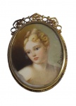 Antigo broche em prata teor 800, com delicado trabalho ornamental e acabamento dourado. A peça apresenta uma miniatura feminina em estilo clássico, protegida por lente frontal. Medindo: 3,5 x 2,5 cm.