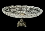 Fruteira em cristal com pé em metal, apresentando belíssimo trabalho lapidado com detalhes florais e borda rica em relevo, com base  ornamentada; medindo: 18,5 x 36 cm