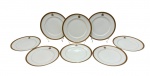 Oito pratos rasos em porcelana, esmaltado na cor branco com elegante faixa superior em em ouro com decoração de arabescos e monograma central. Medindo: 25,5cm.