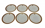 Seis pratos para pão em porcelana, esmaltado na cor branco com elegante faixa superior em em ouro com decoração de arabescos e monograma central. Medindo: 15 cm.