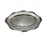 Travessa em metal espessurado a prata da marca Fracalanza, de formato oval com contorno recortado, borda decorada com frisos paralelos e elementos em relevo nos pontos de destaque. Superfície lisa e levemente côncava. Medidas; 38 x 26 cm. Pequenas marcas de uso.