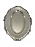 Travessa em metal espessurado a prata da marca Fracalanza, de formato oval com contorno recortado, borda decorada com frisos paralelos e elementos em relevo nos pontos de destaque. Superfície lisa e levemente côncava. Medidas: 33 x 23,5 cm. Leves desgastes no banho e pequenas marcas superficiais.