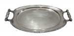 Travessa em metal espessurado a prata da marca Wolff, de formato oval, apresentando alças laterais com acabamento torneado e detalhes em relevo com motivos florais. Borda decorada com frisos delicados e centro liso. Medidas: 54 x 30 cm
