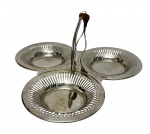 Petisqueira em metal prateado, composta por três compartimentos circulares unidos, com bordas vazadas em delicado trabalho rendado. Possui alça central elevada. Superfícies levemente côncavas. Medidas: 26 x 27 x 11 cm. Apresenta leves desgastes no banho e pequenas marcas superficiais.