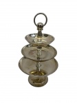 EBERKOC. Doceira de três andares em metal espessurado a prata, composta por pratos circulares em tamanhos progressivos dispostos em haste central com acabamento torneado e alça superior em argola, ideal para servir doces, frutas ou petiscos com sofisticação; altura: 22,5 cm.