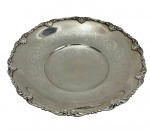 Antiga fruteira em metal espessurado a prata, de formato circular com bordas recortadas e ricamente ornamentadas em relevo, apresentando decoração gravada com motivos florais ao centro e apoiada sobre 3 pés. Medindo; 6,5 x 35 cm.