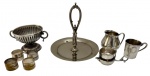 Lote com 9 peças em metal, composto por utensílios de mesa e acessórios diversos, incluindo porta guardanapos, apresentando tamanhos variados; uma peça com pequeno amassado na base e os porta guardanapos necessitando de banho.