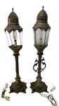 Par de luminárias em metal, com fustes torneados e bases ricamente trabalhadas, apresentando cúpulas com elementos decorativos e vidros lapidados; uma com vidros quebrados e ambas necessitando de banho; medidas: 66 x 17,5 cm.