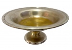 Fruteira em metal espessurado a prata, com corpo em formato de taça sobre pé central, apresentando sinais de uso e necessitando de banho de prata; medidas: 30 x 14 cm.