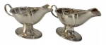 Par de molheiras em metal espessurado a prata, com design clássico, base elevada e alça lateral, próprias para serviço de mesa. Apresentam leves sinais do tempo compatíveis com o uso. Medidas: 21,5 x 10 x 12 cm cada peça.