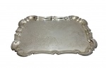 Bandeja em metal espessurado a prata, de formato retangular com bordas recortadas e aba ondulada, ricamente decorada com motivos florais gravados. Peça elegante. Medidas: 48 x 34,5 x 4,5 cm.