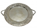 Bandeja em metal espessurado a prata, com alças laterais, apresentando fundo com textura martelada e borda ricamente decorada com motivos florais em relevo. Medidas: 36,3 x 30,5 cm.