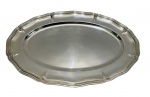 Grande travessa em metal espessurado a prata, de formato oval com bordas recortadas e aba em relevo. Medidas: 49 x 33 cm.