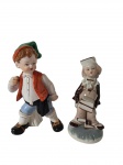 Duas esculturas em porcelana, representando figuras infantis em trajes típicos, com rica policromia e acabamento esmaltado. Uma das peças de origem portuguesa, conforme marca na base. Medidas: 15 x 7,5 cm / 18 x 11 x 8 cm