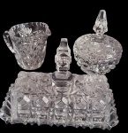 Conjunto de três peças em cristal lapidado, composto por açucareiro com tampa, cremeira com alça e manteigueira, todas com rica lapidação em padrões geométricos. Medidas: 18,5 x 9,5 x 15 cm / 8,5 x 8 x 10 cm / 10 x 15 cm