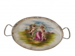 Bandeja em faiança decorada com cena central em policromia representando mulher com cupidos em paisagem campestre, com rica composição de inspiração clássica. Possui galeria e alças em metal. Medidas: 4 x 39 x 22 cm.