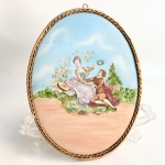 Quadro oval para parede, produzido em placa de porcelana com pintura de cena galante em policromia emoldurado em bronze. Med 26 x 20 cm.