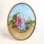 Quadro oval para parede, produzido em placa de porcelana com pintura de cena galante em policromia emoldurado em bronze. Med 26 x 20 cm.