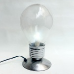Luminária contemporânea de mesa em formato de lâmpada, base prateada. Funcionando. Med 31 cm.