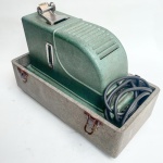 Antigo projetor de slides, acondicionado em maleta original, funcionando lâmpada e motor. Cerca de 40cm de comprimento.