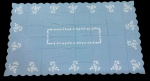 Toalha de mesa em linho na cor azul, ricamente decorada com bordados em branco formando motivos florais distribuídos ao longo das bordas e em composição central retangular. Medidas: 2,80 x 1,65 m.