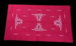 Toalha de mesa em tecido vermelho, ricamente decorada com bordados em branco formando elaborados motivos florais e arabescos distribuídos pelo campo central e bordas. Medidas: 2,90 x 1,62 m.