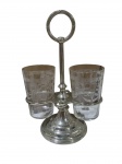 Elegante suporte em metal, com base circular e haste central com alça superior. Acompanha dois copos em cristal com delicada decoração gravada. Medidas do suporte: 26 x 17 cm. Medidas dos copos: 7 x 11 cm.