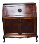 Antigo móvel escrivaninha em madeira nobre, com tampo superior basculante, gaveta frontal e duas portas inferiores, revelando interior compartimentado com divisórias para pastas e acessórios. Apresenta acabamento em lâmina de madeira com desenho em padrão radial e pés levemente curvos. Medidas: 88 x 102 x 49 cm.