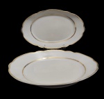 Real. Duas travessas em porcelana nacional esmaltada na cor branca, com bordas onduladas e filetes em ouro. Medidas: 40 x 26 x 6 cm 36 x 23 x 5 cm. Em ótimo estado.
