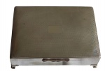 Antiga caixa retangular em metal espessurado a prata, de procedência inglesa. Estrutura apoiada sobre quatro pés baixos. Interior revestido em madeira, com divisória interna formando dois compartimentos. Medindo;16,5 x 12 x 4,5 cm.