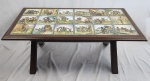 Mesa auxiliar com azulejos Mesa retangular baixa de centro executada em madeira nobre. Tampo com 18 azulejos diversos em policromia: Ilustrações do livro Dom Quixote de La Mancha, do escritor espanhol, Miguel de Cervantes (1547-1616). A história relata os feitos de um ingênuo e fidalgo cavaleiro medieval, Dom Quixote. Ao lado dele, estão seu cavalo Rocinante e seu fiel amigo e escudeiro, Sancho Pança. Medindo: 39 x 54 x 99 cm.