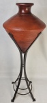 Vaso no feitio de pião em barro cozido com suporte em metal patinado. Medida total: 100 cm, suporte: 80 x 26 cm e vaso: 43 x 35 cm.