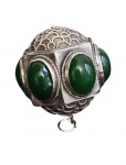 Pingente confeccionado em prata, de formato esférico com estrutura vazada e rica decoração em filigrana, aplicado com cabochões de pedra verde (possivelmente ágata ou jade). Peso: 27,7 g.