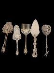 Lote composto por quatro talheres de servir, confeccionados em metal espessurado a prata, incluindo peças com bojos vazados e sólidos, apresentando ricos detalhes ornamentais em relevo e diferentes estilos de cabos, característicos de distintas épocas.