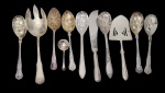 Lote composto por talheres de servir variados, incluindo colheres, garfos e espátulas, confeccionados em metal com acabamento prateado, apresentando diferentes padrões decorativos em relevo e estilos de cabos, característicos de distintas épocas. Tamanhos variados.