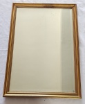 Espelho bisotado, de formato retangular, moldura em madeira com patina dourada.Medindo: 67 x 46 cm. Pequeno pontos de manchas no espelho.