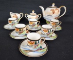 JAPAN - Serviço de café em porcelana japonesa, decorado com paisagem lacustre e pagodes em policromia e farta douração. Composto de: um bule (14 cm alt), cremeira (7 cm), açucareiro (9 x 11 cm) e 6 xícaras para café com seus pires. Um pires com bicado na borda.