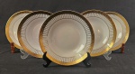 Seis pratos fundos em porcelana branca com rica decoração em ouro. Aba com friso ornamentado e fileiras de pontos em relevo/douração, formando composição elegante e clássica. Verso com marca de fábrica em dourado. Medidas: 3,5 x 20 cm.