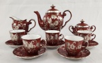 Real. Conjunto de café em porcelana, composto por bule, leiteira, açucareiro com tampa, cinco xícaras com respectivos pires e um pires avulso. Decoração em esmalte vermelho profundo, ricamente ornada com motivos florais estilizados em aplicação de prata de lei, com delicados arabescos. Interior das xícaras em branco, criando contraste com o exterior. Manufatura no verso.