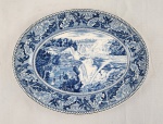 Historic America  Niagara Falls, da Johnson Bros., England. Travessa oval em porcelana inglesa, decorada em azul sob fundo branco, apresentando cena clássica com rica composição, ornamentada com elaborado motivo vegetal, padrões tradicionais britânicos. No verso, marca da manufatura. Medidas: 23 x 30 cm.