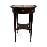 FRANÇA - Mesa auxiliar em estilo francês napoleônico, em madeira nobre, com gaveta frontal, frisos entalhados e ferragens em metal dourado. Elegante peça de linhas finas e leveza clássica. Tampo circular com nível inferior. Marcas do tempo. Virada do século.. Mede 71 cm altura x 50 cm diâmetro.