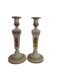 ITALIA - Par de castiçais em porcelana italiana Capodimonte, ricamente decorados com cenas clássicas de figuras humanas em relevo policromado, detalhes em douração e base trabalhada. Peças elegantes, de fino acabamento, típicas da tradição italiana decorativa do século XX. contorno em vibrante ouro. Mede 32 cm altura.