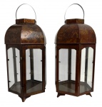 Par de imponentes lanternas em metal patinado, com corpo facetado e painéis envidraçados. Cúpula superior perfurada, alça metálica para transporte ou suspensão e base com pés. Peças de estética clássica, ideais para iluminação decorativa de ambientes internos ou externos cobertos. Conjunto harmonioso, de bom porte e efeito ornamental. Mede 72 cm altura x 30 cm.