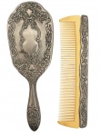 Conjunto de toucador, composto por escova de cabelo e pente, com estrutura em metal prateado ricamente ornado e peças em material sintético em tom marfim. Mede 20cm.